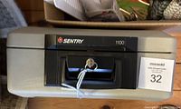 Top view of the closed Sentry 1100 document safe showing the lock, handle, and attached key.