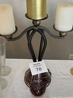 Three arm metal candlestick holder with three white pillar candles, heavy base, brass accents.