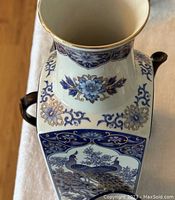 Close-up photo of the square vase with blue floral and peacock patterns, gold rim detail