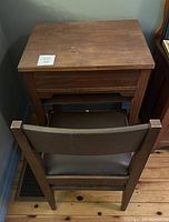 Full view of the vintage wooden sewing table with a wooden chair in front, showing the table's surface and chair back
