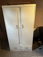 White wood armoire with two doors and metal handles with two drawers at the bottom, full front view