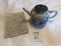 Photo of the teapot with an old note describing its origin and dating it between 1680-1765.