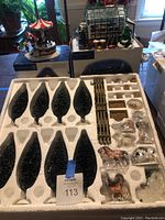 Styrofoam tray containing 4 large black snow-dusted poplar trees, fence sections, and farm animal figurines in plastic wrap