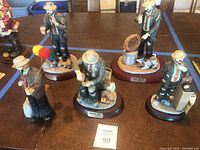 Five Emmett Kelly clown figurines displayed on table lined with blue tape showing all figurines in lot