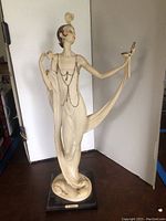 Full view of the Lady and the Mirror statue depicting an elegant woman in a cream dress holding a mirror, standing on a black base with a nameplate.