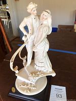 Full view of the porcelain bride and groom figurine showing the detailed clothing and stair base with floral design.