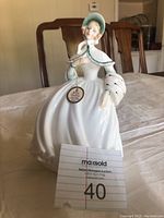 Front and side angle of Royal Doulton Jessica figurine showing full figure, dress, bonnet, and attached tag.
