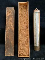 Full view of antique candy evaporator thermometer with original rough hewn pine box with sliding lid and straw filler.