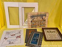 Five textile and paper artworks including two linen samplers, two mats, one frame, papyrus artwork, and two small silk tapestries shown together.