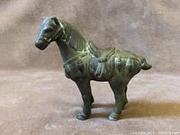 Front and left side view of the bronze horse figurine showing detailed saddle and sculpted mane.