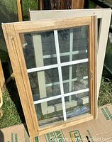 Photo showing one window with wood finish sash and interior white grille, glass pane, exterior coated white.