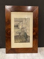Framed artwork showing the entire piece including the hardwood frame and matting against a black background.