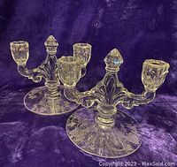 Pair of clear glass floral etched dual candle holders on purple fabric background