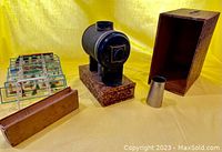 Overall view showing magic lantern projector, wooden case, glass slide racks with slides, and metal accessories on yellow background