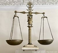 Front view of brass scales with marble base showing Lady Justice figure and brass pans suspended by chains