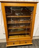 Front view of the oak curio cabinet showing glass door and two lower drawers