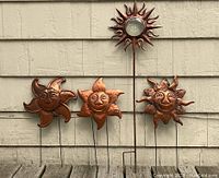 Four copper finished tin sun yard stakes. Three measure 11" W x 20" H with double stakes, smiling faces and different sunray designs. One taller sun 11" W x 36" H has a pressed glass face insert and double-pronged stake. All are intended for outdoor garden decoration.