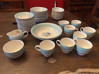 Full dessert set displayed on wood table, showing various bowls, cups, sugar and creamer.