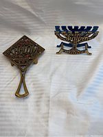Two Judaica items on white background: a napkin holder and spoon rest/trivet featuring Shalom in decorative Hebrew style.