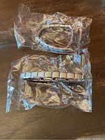 Two magnetic therapy bracelets sealed in clear plastic packaging on a wooden surface.