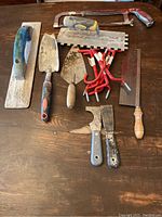 Collection of miscellaneous hand tools on wooden surface.