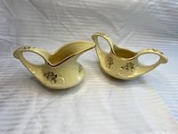 Both sugar bowl and creamer shown together on white fabric background, clear view of shape and gold trim.