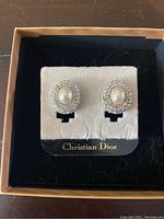 Front view of the clip-on earrings featuring oval faux pearl center surrounded by rhinestones on original Christian Dior placard.