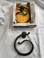Two black wrought iron towel holders by Umbra in original box, showing hammer texture and circular design