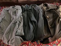 Four women's jackets laid out on a patterned rug showing various styles and colors including polka dot, black, and brown wool.