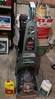 Front view of Bissell PROheat 2X Healthy Home carpet cleaner upright machine with two bottles of shampoo on floor in front.