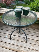 Full view of Homecrest round bistro table with textured tempered glass top and metal frame, showing table and candle placement.