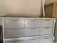 Front view of six drawer white metal cabinet with handles.