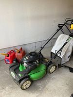 Angled view of mower with gas cans and rear bag
