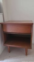 Front view showing drawer and lower shelf of wooden mid-century night stand.