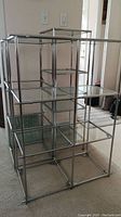 Front and side view of modular shelving unit showing chrome frame and glass panels