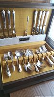 Full view of Oneida silver plate flatware set for 8 displayed in a wood and fabric lined canteen case, showing forks, knives, spoons and additional serveware.