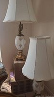 Pair of mid century lamps with white fabric shades and glass and gold-tone metal bases, 38 inches tall.