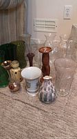 Full view of approximately 20 assorted glass and ceramic vases on carpeted floor showing variety of colors, shapes, and sizes.