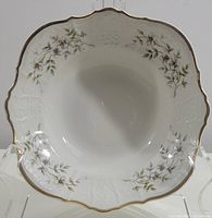 Top and angled view of the scalloped square porcelain bowl showing blossom pattern and gold trim on the rim.