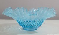 Side view showing the hobnail texture and ruffled rim of the blue opalescent glass bowl