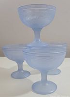 Four powder blue glass dessert bowls stacked, showing shape and size