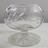 Side view of vintage heavy cut crystal rose bowl showing etched tulip and leaf pattern on bowl and starburst pattern on pedestal base.