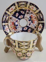 Porcelain cup with intricate Imari floral and gold design in front of matching saucer