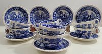 Eight SPODE Blue Transferware Tea Cups arranged in front of their matching saucers with intricate blue scenic designs visible on each piece.