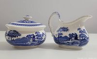 Front view of blue and white Spode Blue Tower creamer and sugar bowl with lids, showing detailed transferware pattern and overall condition.