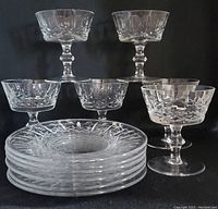 Front view of six crystal dessert cups and six matching saucers arranged on black background.