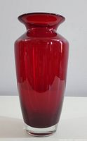 Front view of vintage ruby red glass vase showing smooth glossy finish and clear glass base.