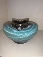 Side view of decorative pottery vase showing blue and black glaze with metallic silver rim