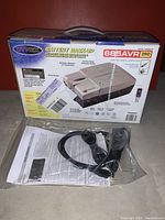 Front and side view of the Dynex TE685AVR Battery Backup original box, unit specifications, with sealed power cord and manual in plastic bag displayed below the box.