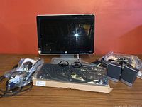 Photo of full lot showing HP monitor, keyboard, two mice, speakers, and bundle of cords on wooden tabletop against orange wall background.